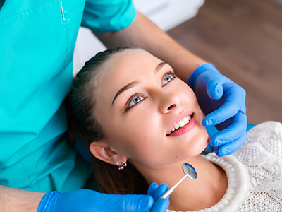 The image shows a person receiving dental care from a professional using a dental drill.